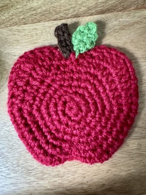 Completed crochet apple coaster in red, showing the back side 