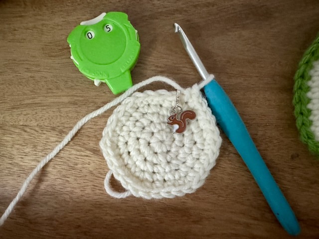 Cream yarn crocheted into a circle at round 5 of pattern