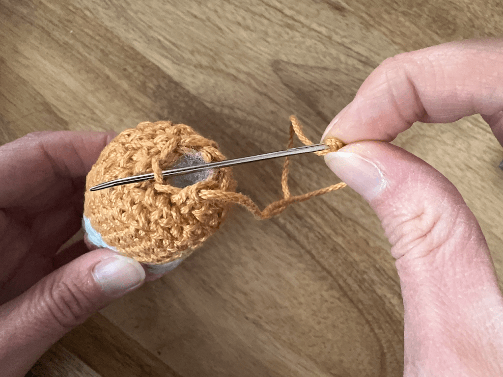 Top of crochet pencil gnome demonstrating weaving through FLO with a tapestry needle